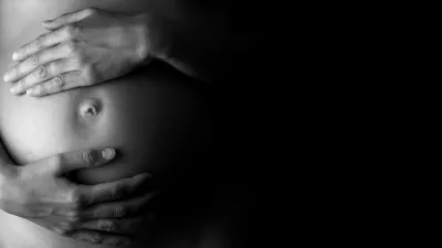Black and white image of hands on a pregnant belly
