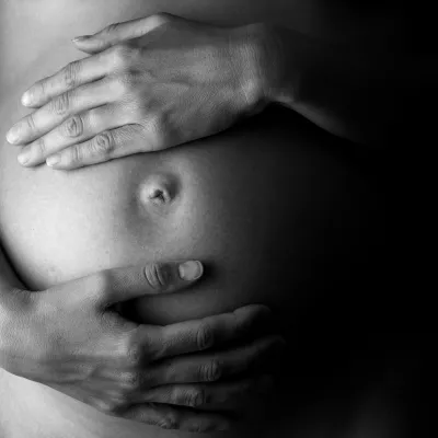 Black and white image of hands on a pregnant belly