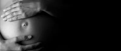 Black and white image of hands on a pregnant belly