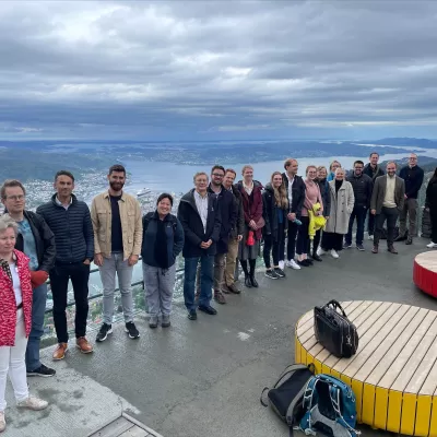 Participants at a Nordic GBD Workshop visit Mount Ulriken in Bergen, Norway. The ocean sits in the backdrop of this group photo.